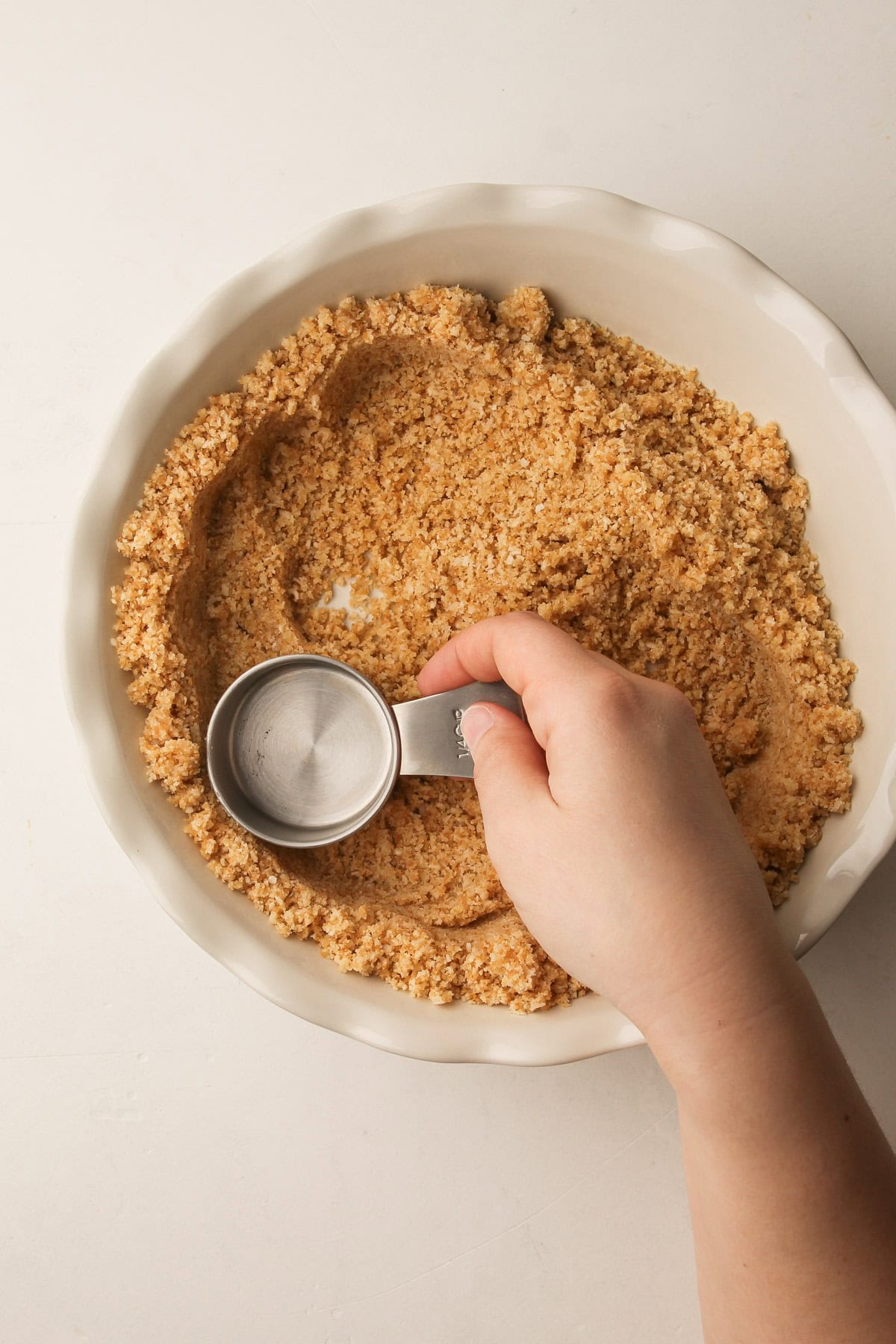 Pressing vanilla wafer crust into a pie plate for coconut cream pie.