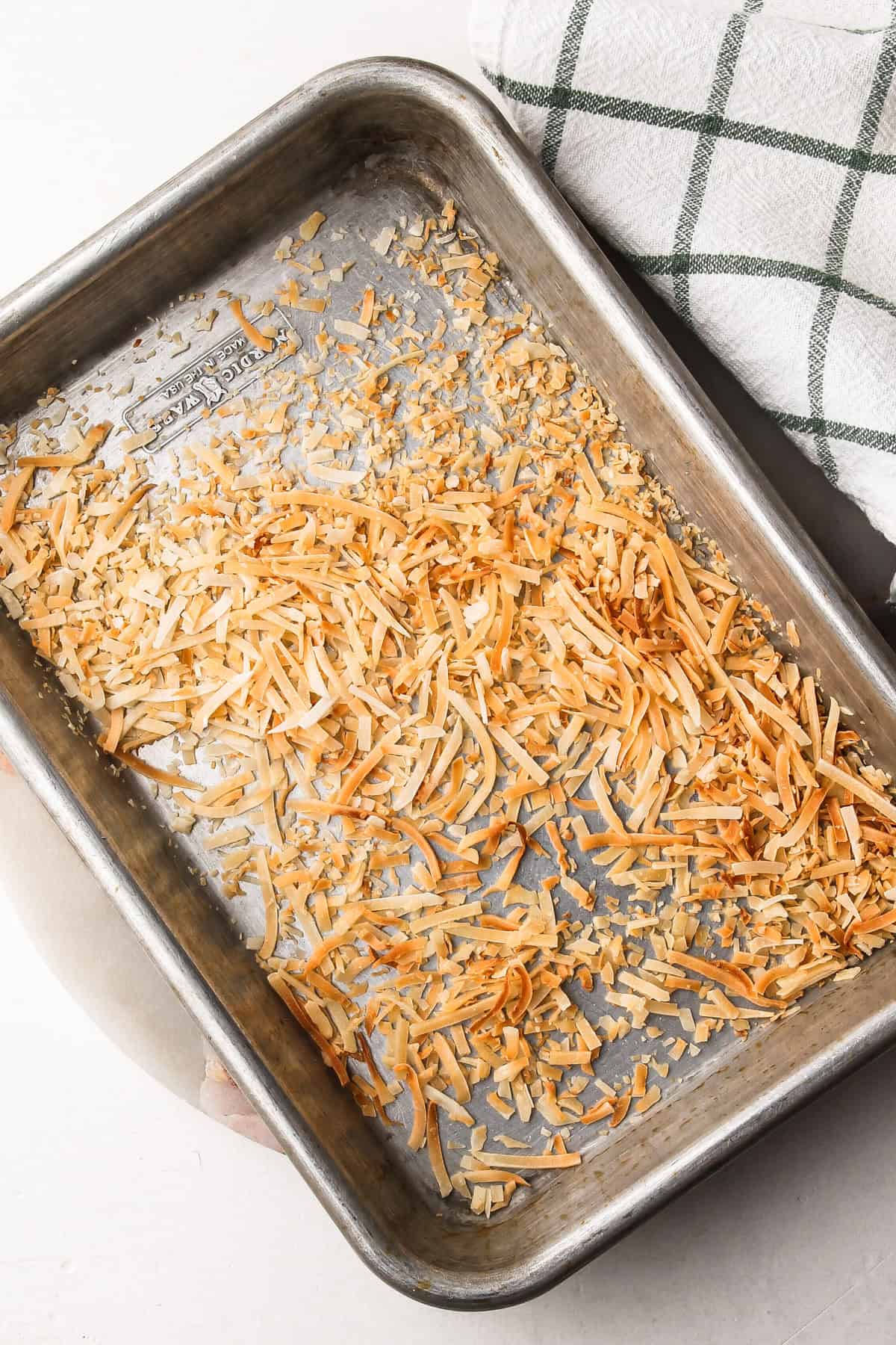 Toasted coconut flakes cooling on a sheet pan for topping coconut cream pie.