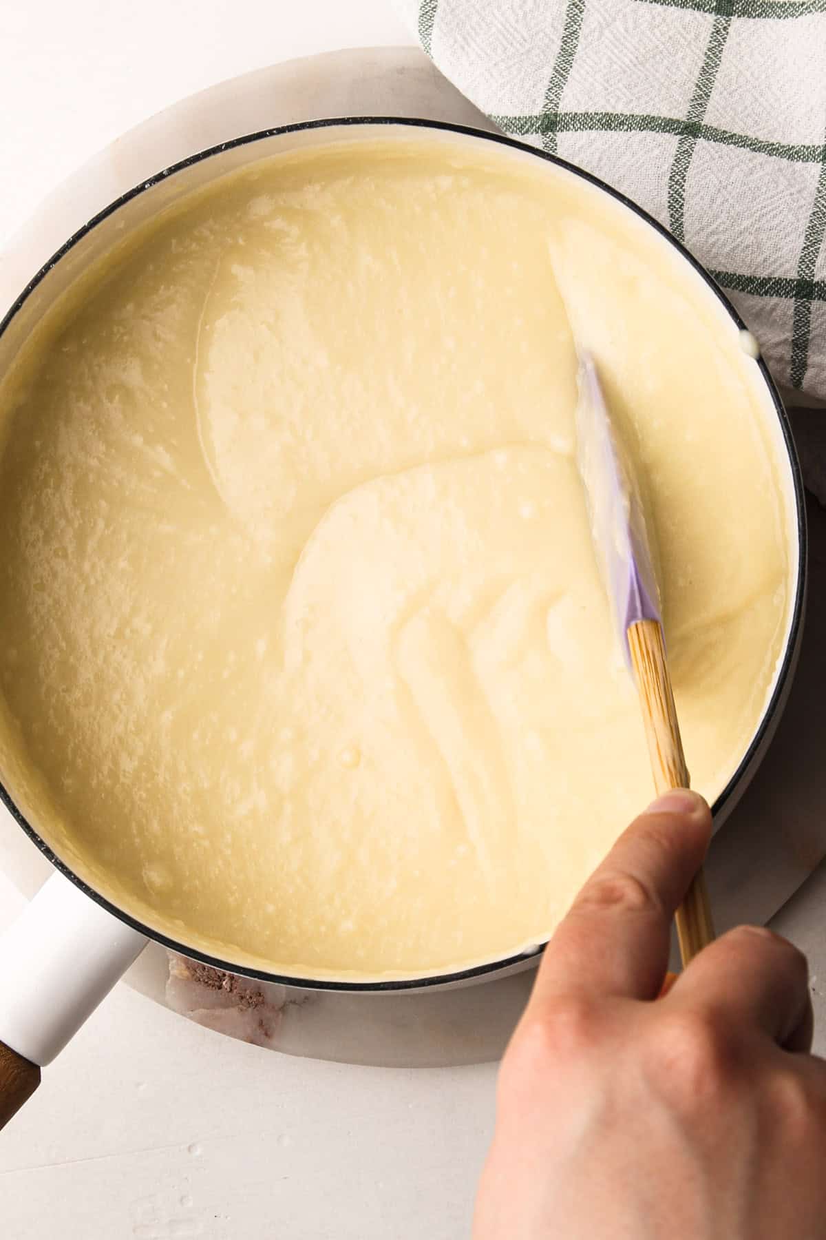 Stirring thickened coconut custard in a saucepan for classic coconut cream pie.