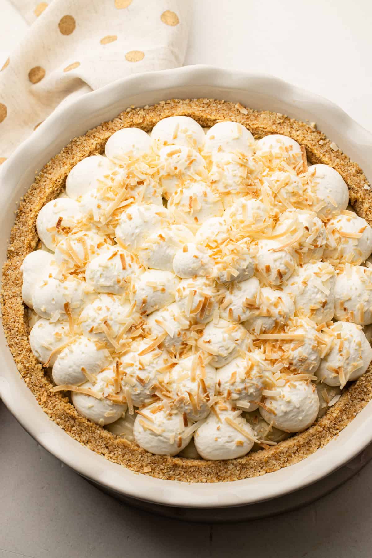Fully assembled classic coconut cream pie topped with whipped cream and toasted coconut.