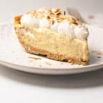 Close-up of a slice of coconut pudding pie on a plate with golden toasted coconut garnish.