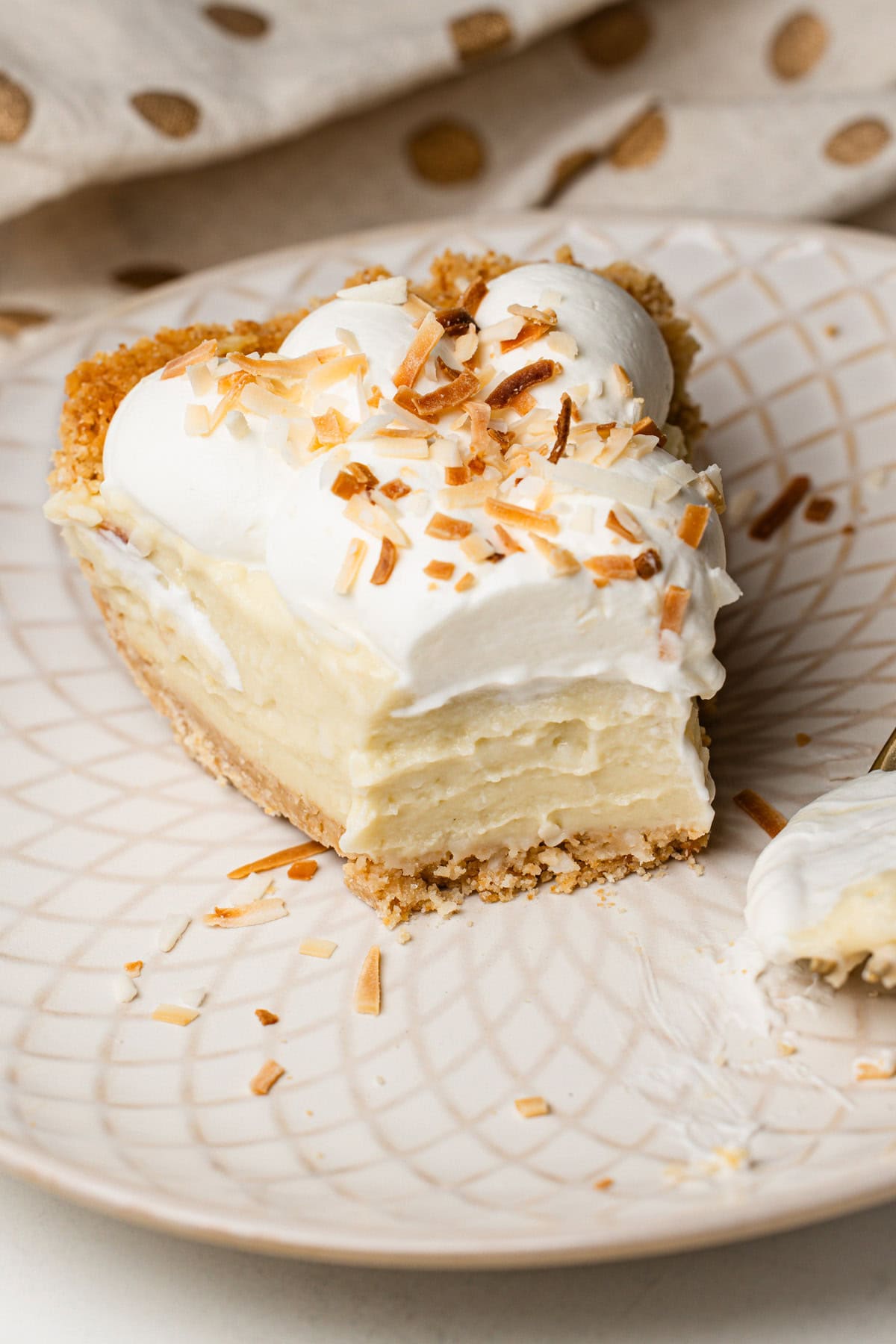 Close-up of a partially eaten coconut cream pie slice, highlighting the smooth, chilled pudding.
