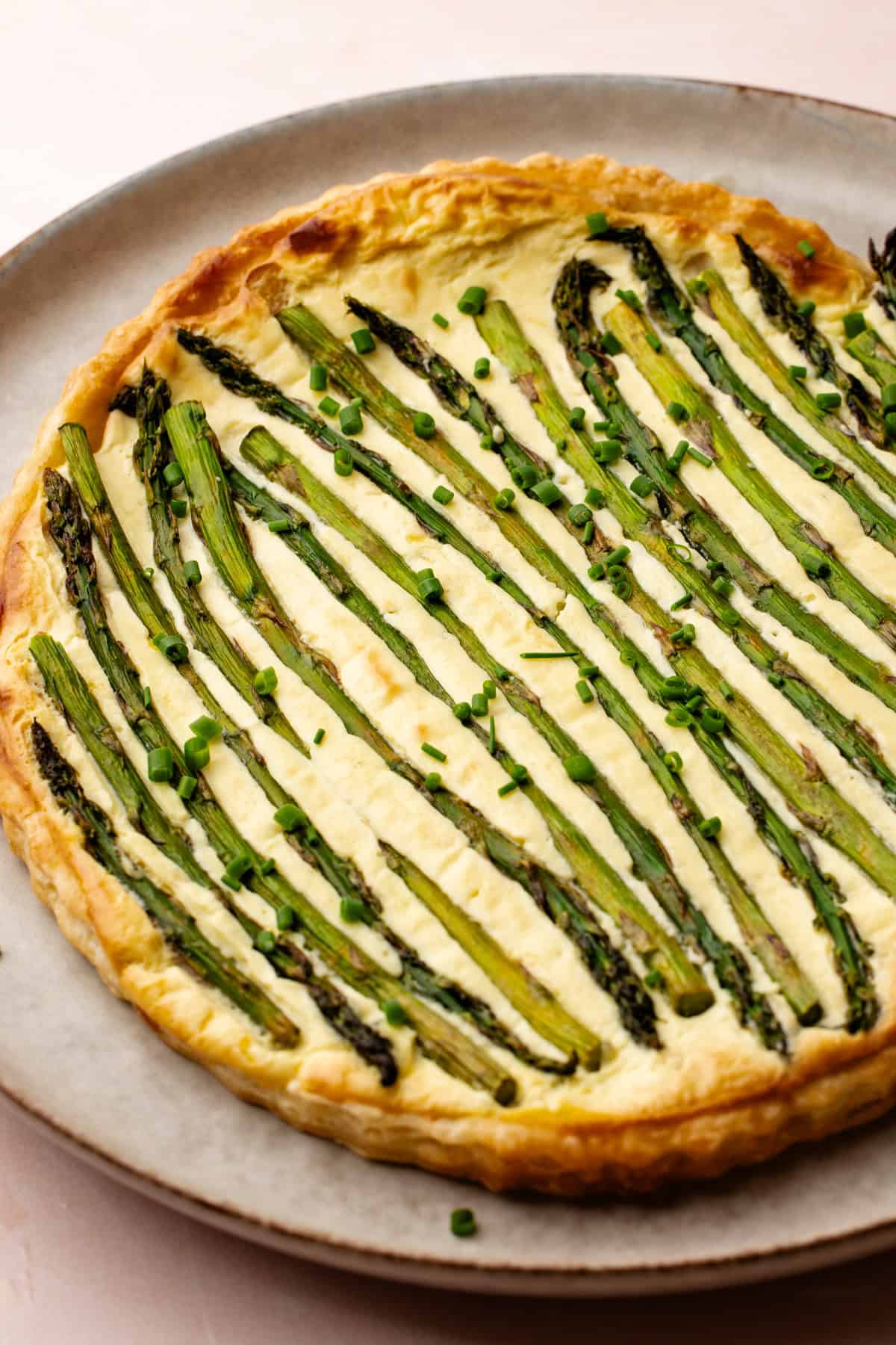 A baked lemon asparagus tart topped with roasted asparagus and chopped chives.
