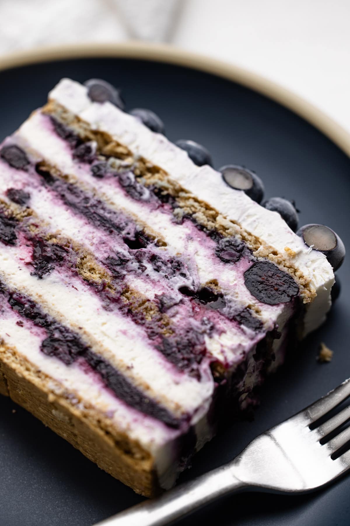 A slice of blueberry icebox cake on a blue plate.