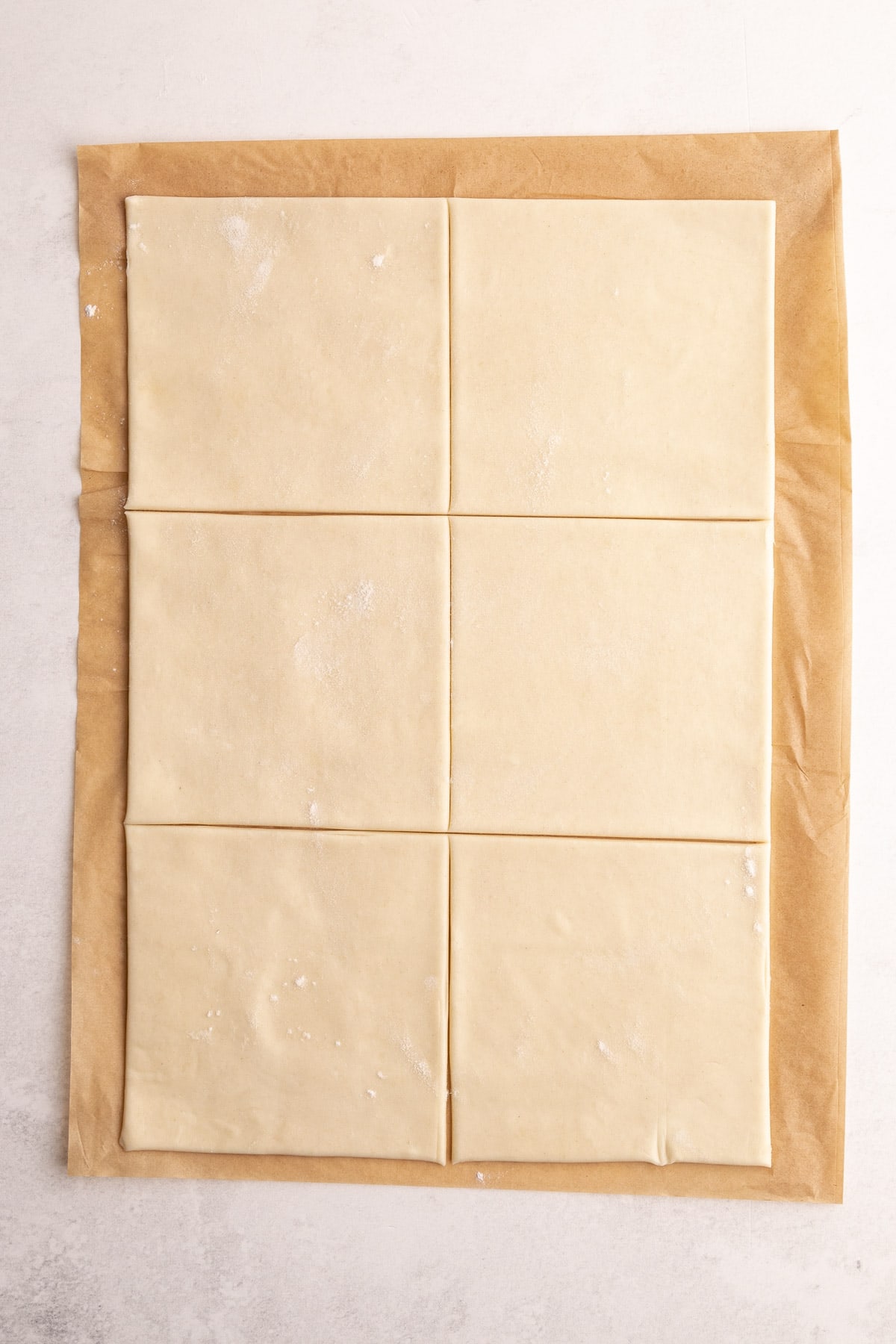 Six squares of dough being cut out for turnovers.
