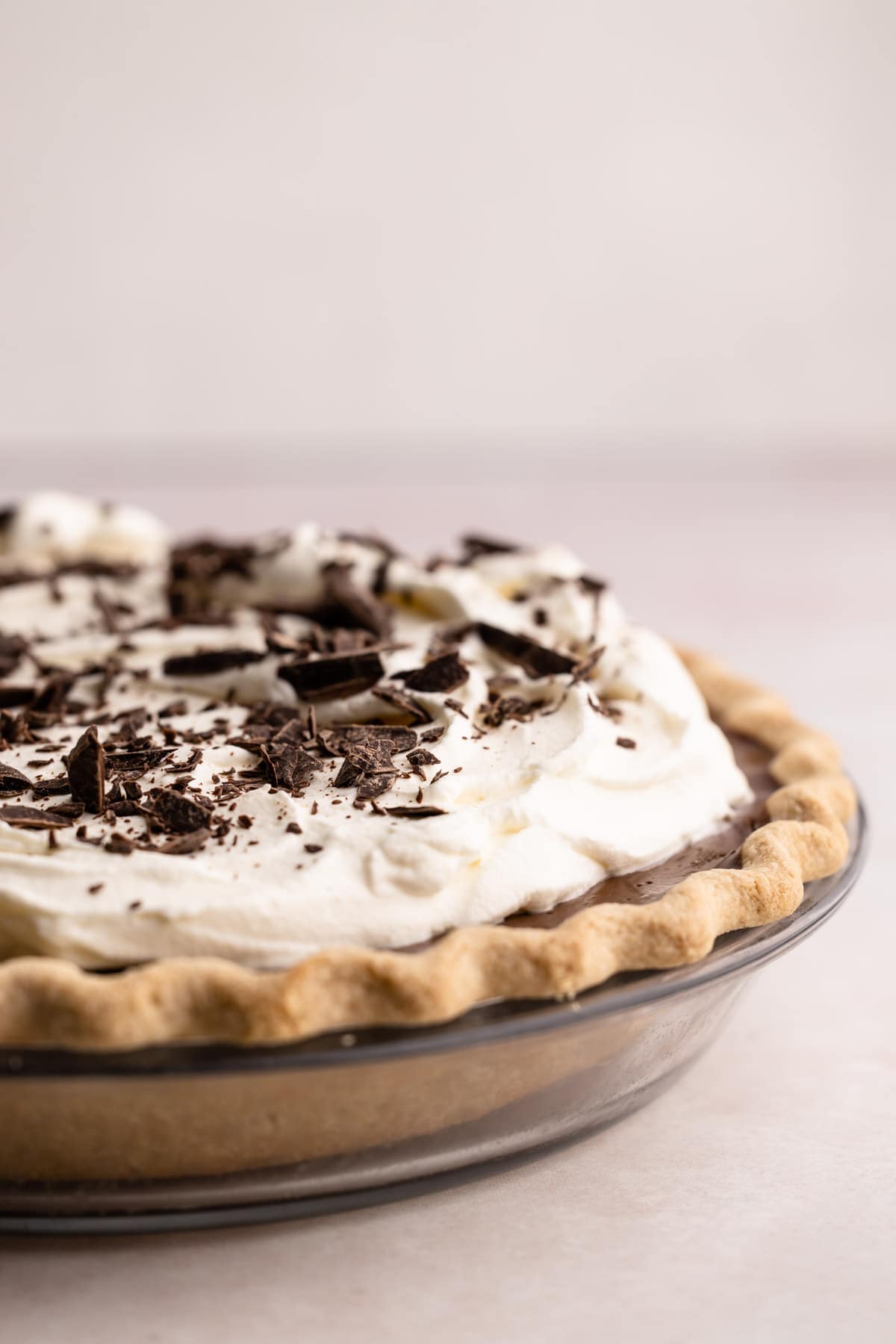A chocolate cream pie piled high with whipped cream and chopped chocolate.