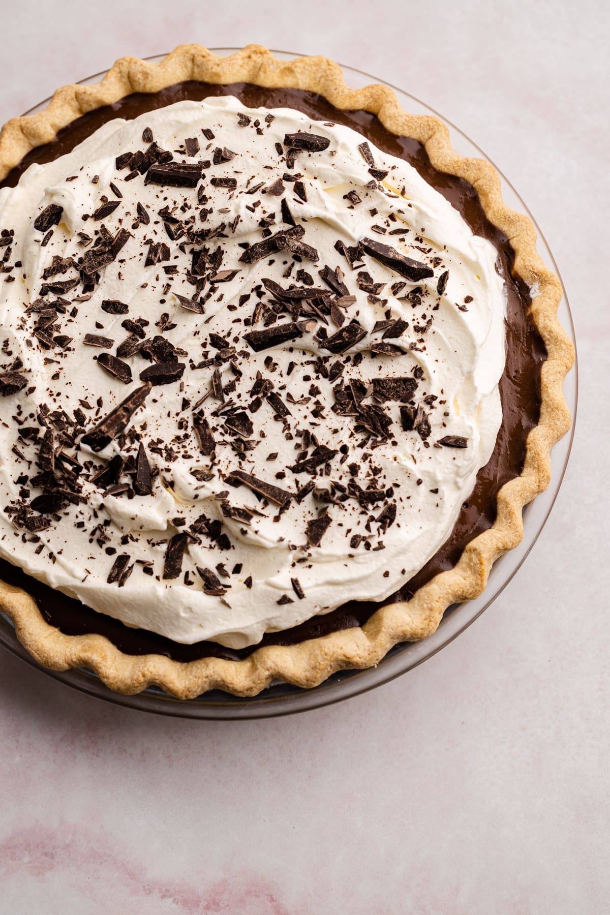A fully assembled chocolate cream pie decorated with chopped chocolate.