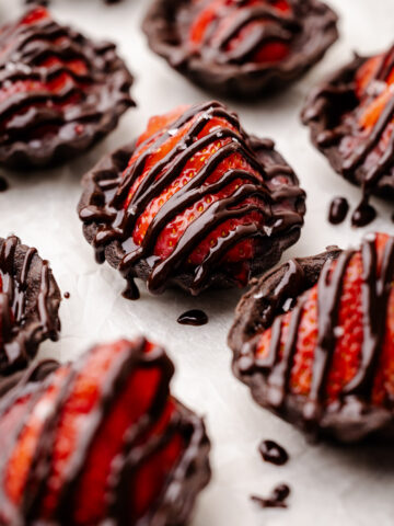 Chocolate strawberry tarts drizzled with melted chocolate.
