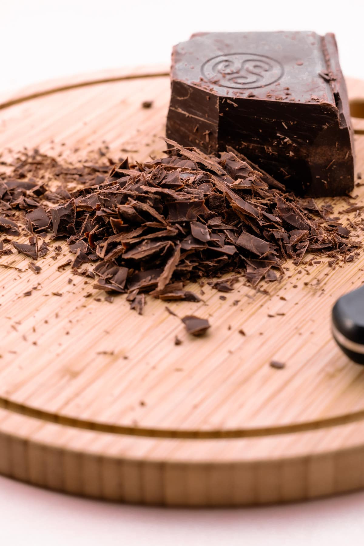 A bar of partially chopped chocolate on a cutting board.