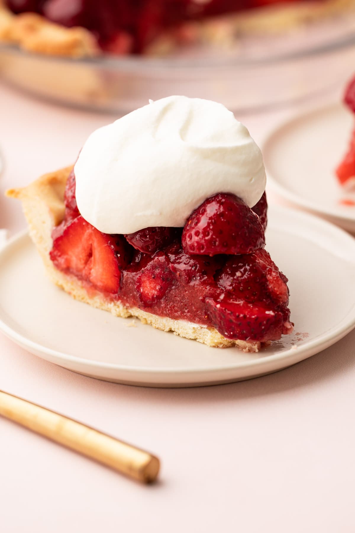 A slice of fresh strawberry pie with a dollop of cream on top.