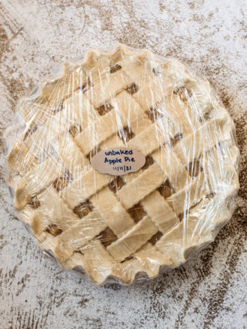 A frozen apple pie wrapped in plastic wrap and labelled.