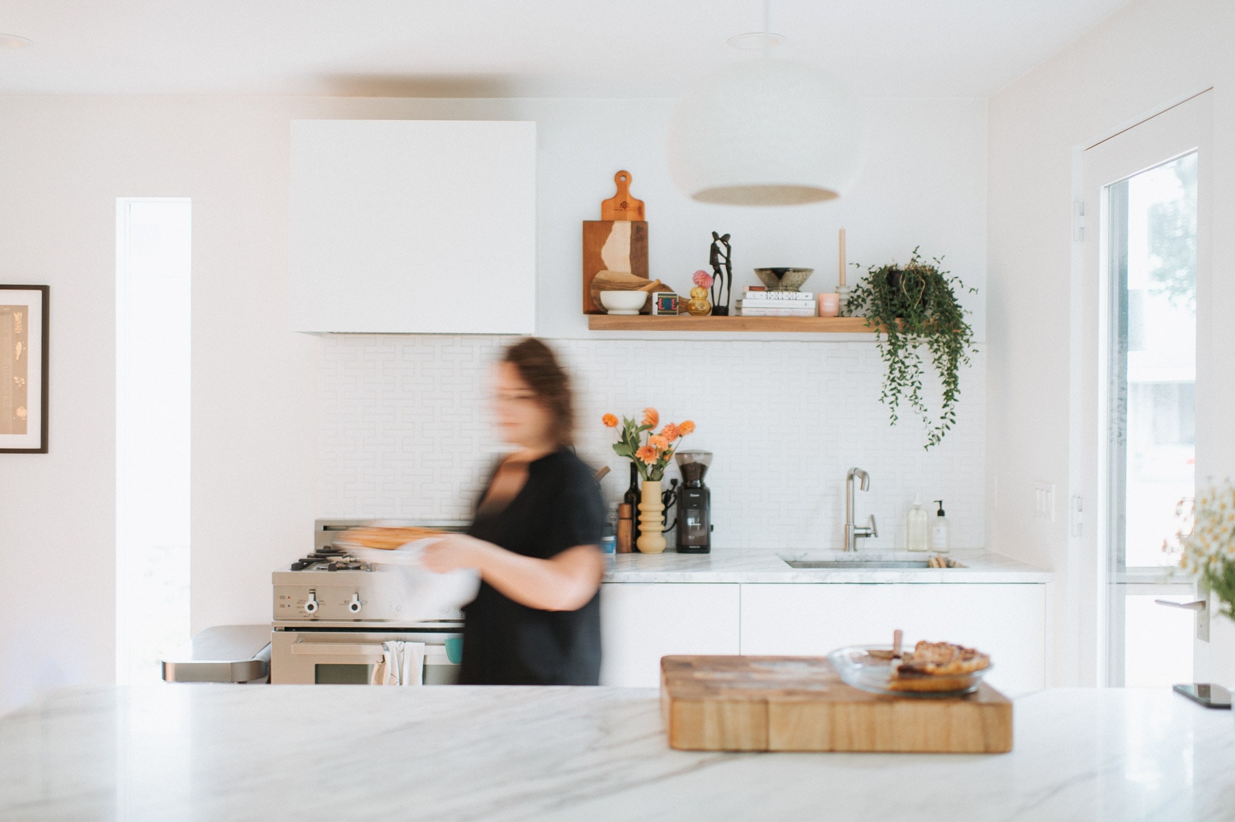 A blurred image of Kelli Avila, creator of Everyday Pie, carring a pie through a kitchen.
