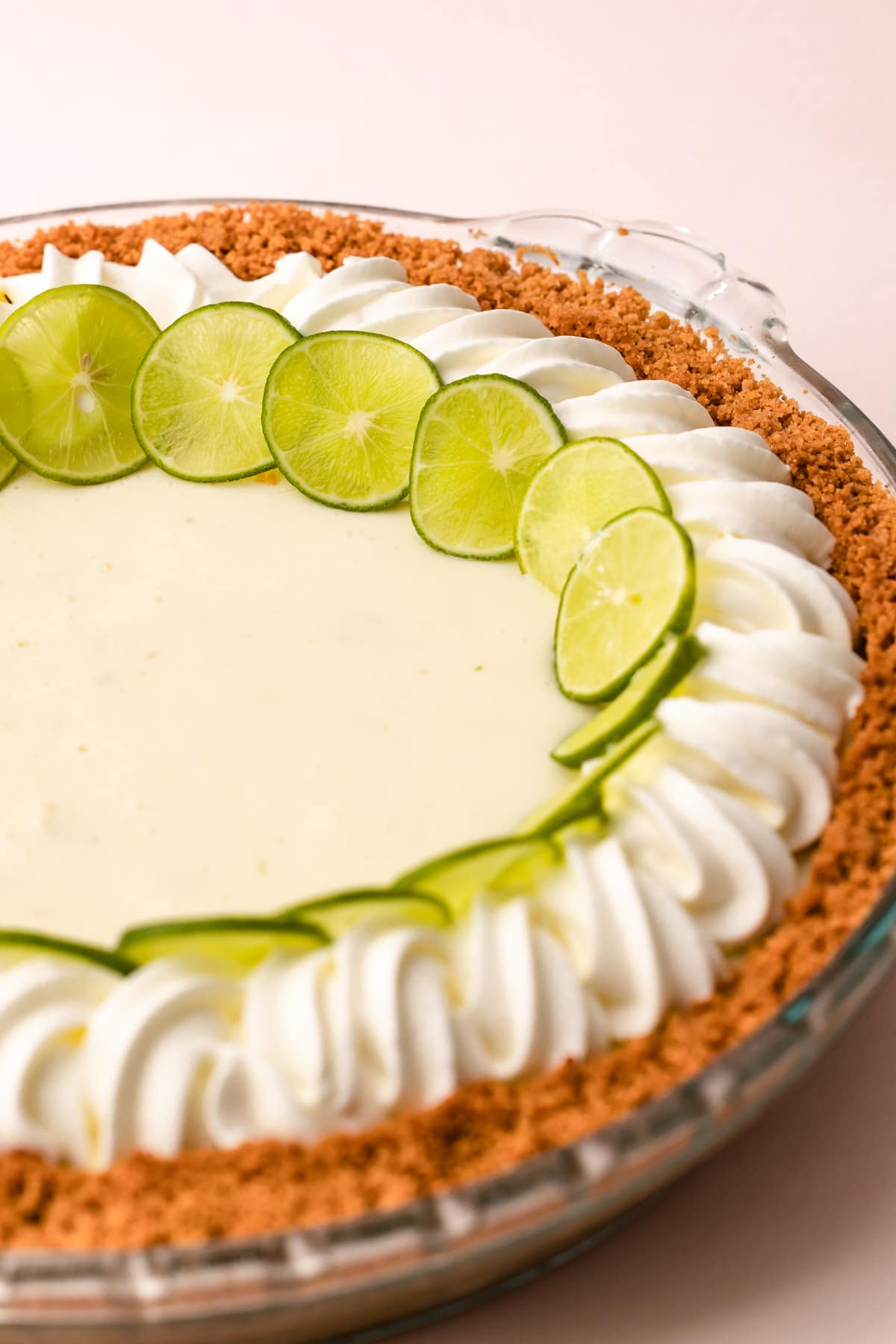 A key lime pie decorated with whipped cream and sliced limes.