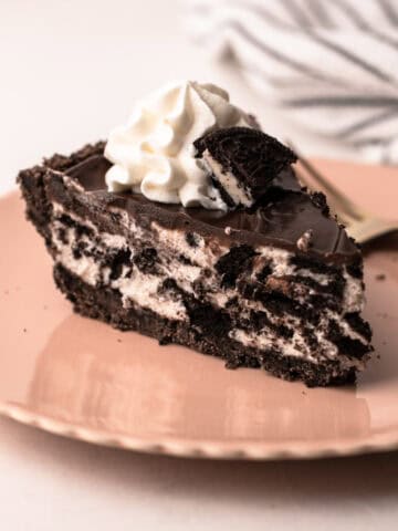 Single slice of easy oreo pie on a plate with whipped cream.