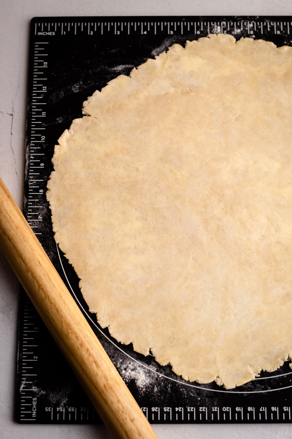 A rolled out pie crust on a pastry board.