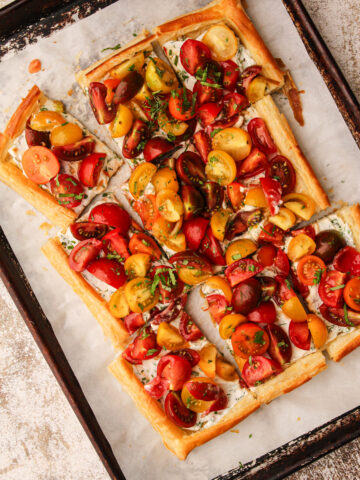 A fully baked tomato tart made with puff pastry sliced up.